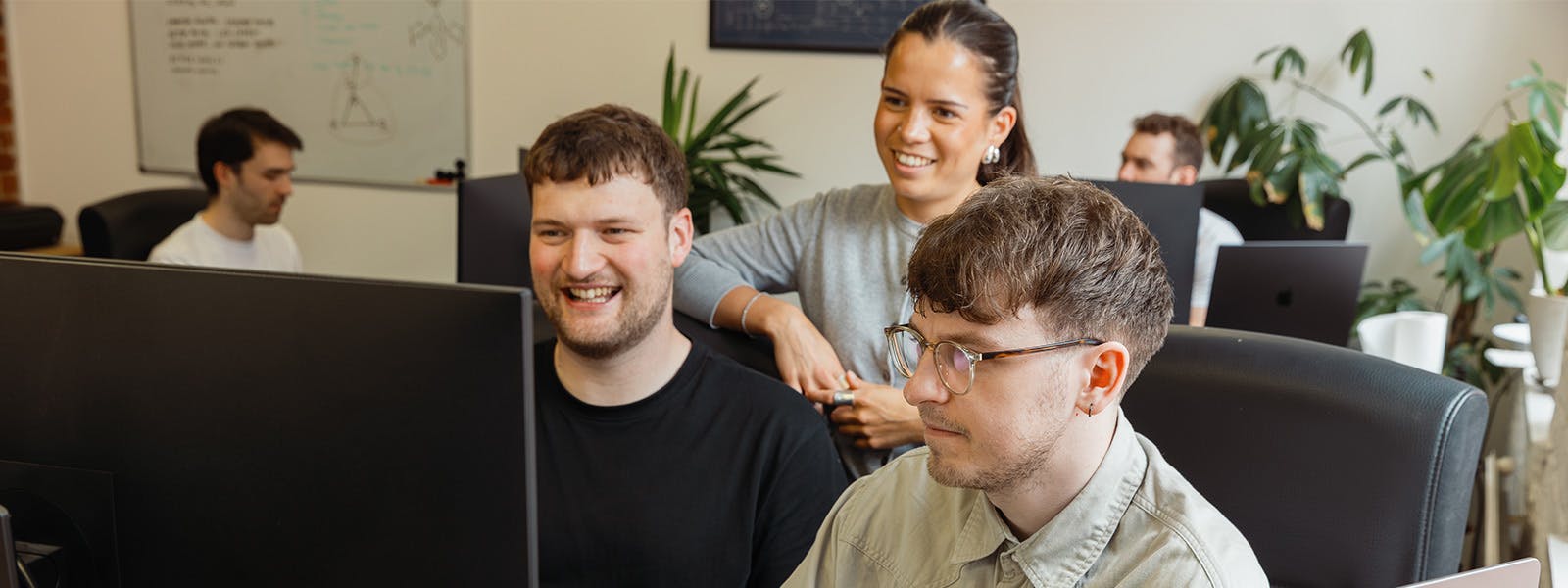 Two men and one woman looking at computer screen