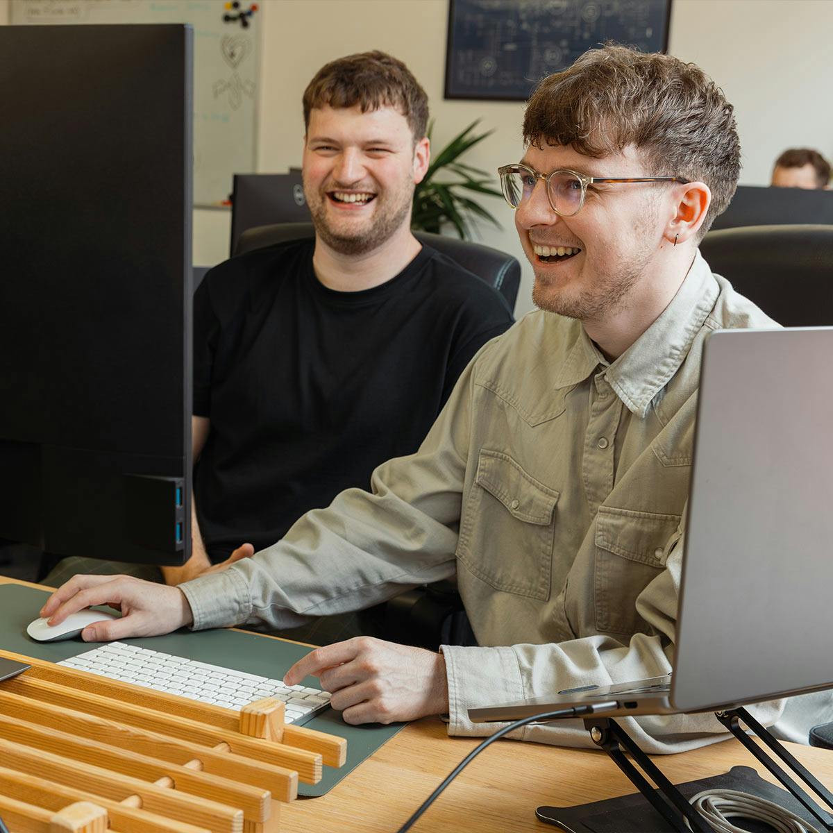 Two white men smiling at a computer
