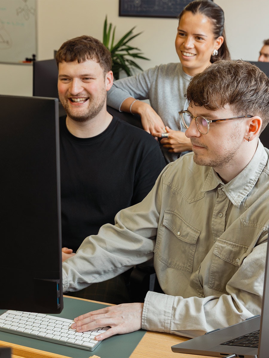 madeby.studio Team around a computer smiling