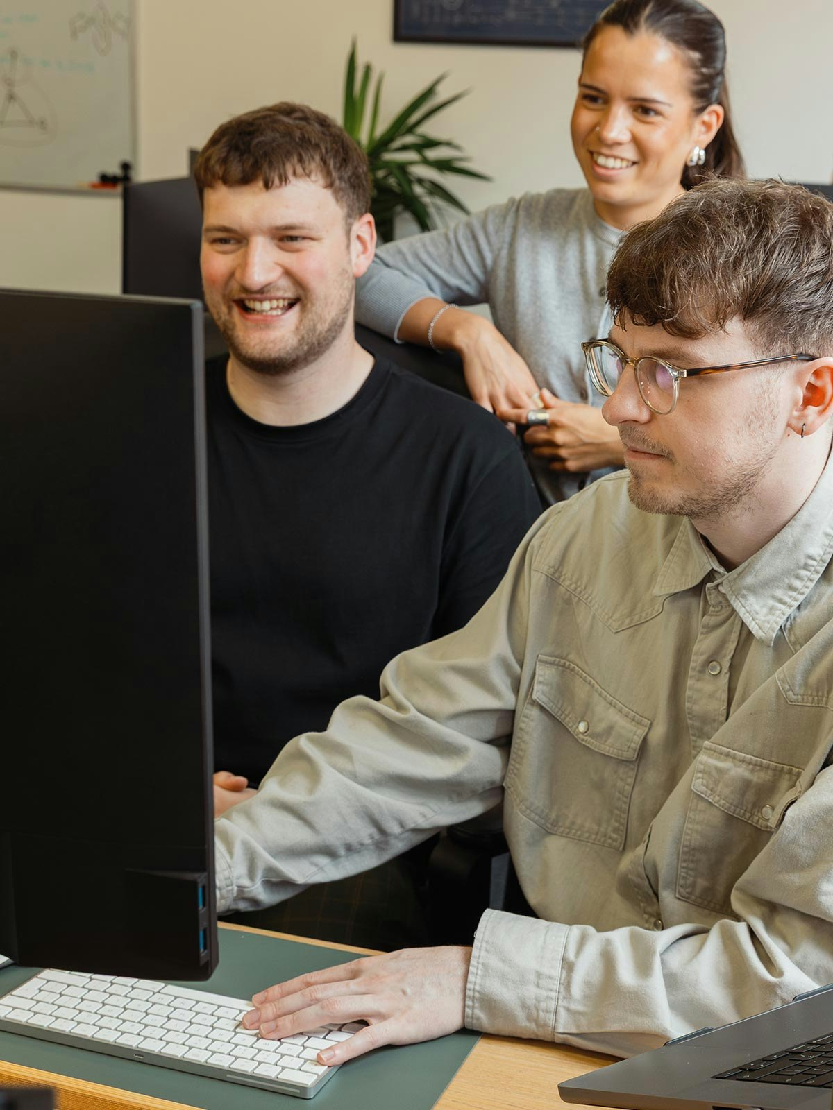 Three members of madeby.studio working at a computer